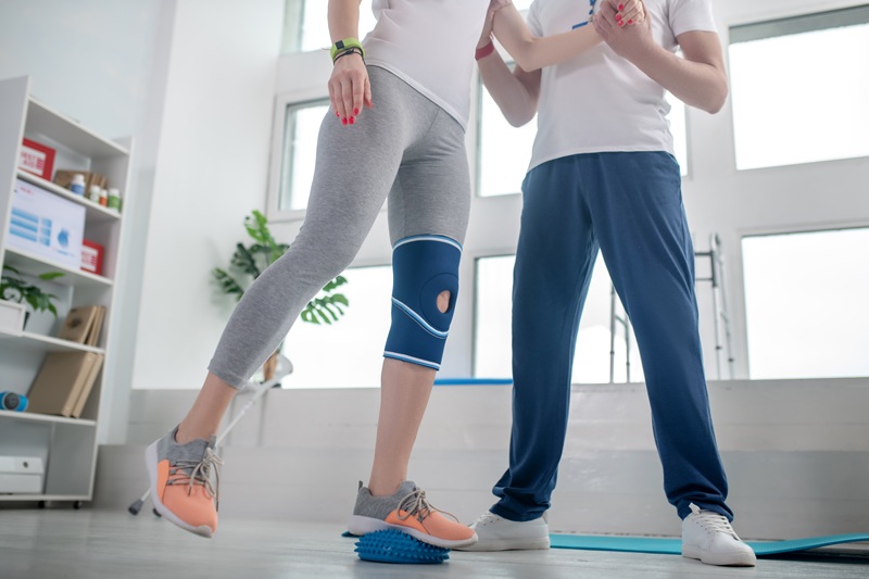 At physical therapy center. Male physiotherapist helping female patient with balance exercises