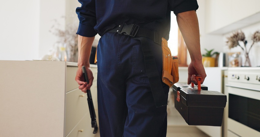 Back, plumber and tools in kitchen for maintenance, service and professional help for leak. Man, co.